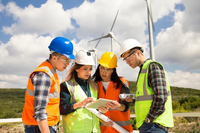 people standing in front of a wind farm