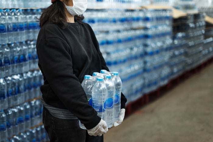 woman-carrying-drinking-waters-with-gloved-hands-during-coronavirus-pandemic-1